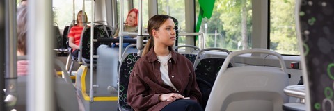 Opiskelija istuu linja-autossa ja katsoo ulos ikkunasta