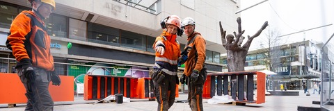 Kuvassa rakennetaan viherkeidasta ja asetellaan iloisen oransseja elementtejä paikoilleen