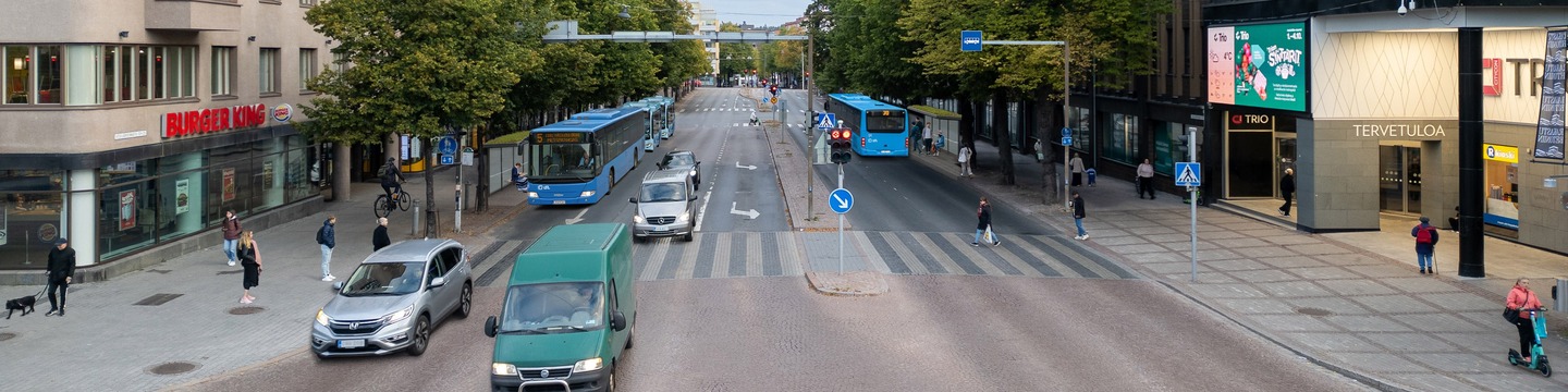 Havainnekuvassa autot ajavat pitkin Vesijärvenkatua. Kauppakeskus trion kohdalla on kadun molemmin puolen linja-autopysäkkejä katoksineen ja penkkeineen. Havainnekuvan on tehnyt Ramboll.