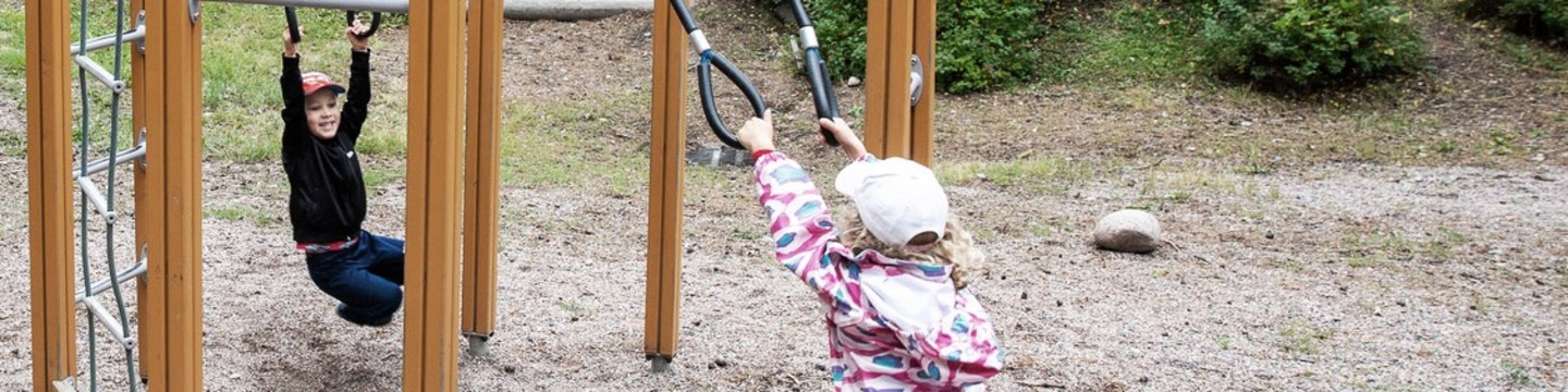 Lapsia leikkimässä ulkona puisessa leikkivälineessä