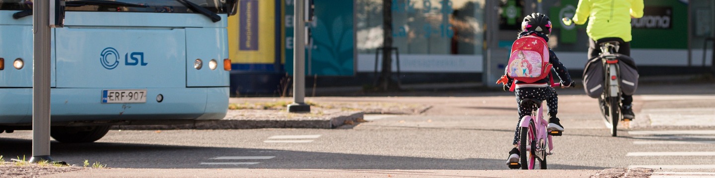 Lapsi ajaa pyörällä reppu selässä