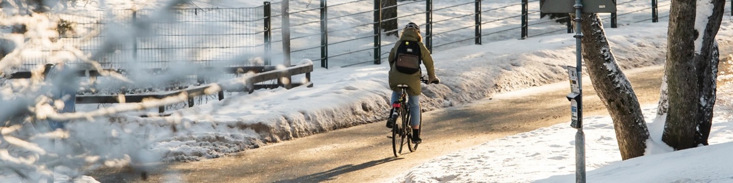 Pyöräilijä ajaa talvella pyörätietä pitkin